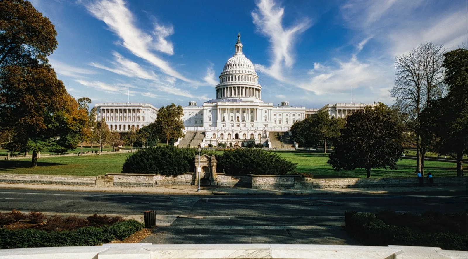 The Capitol dome across its tree-lined grounds under a streaked sky