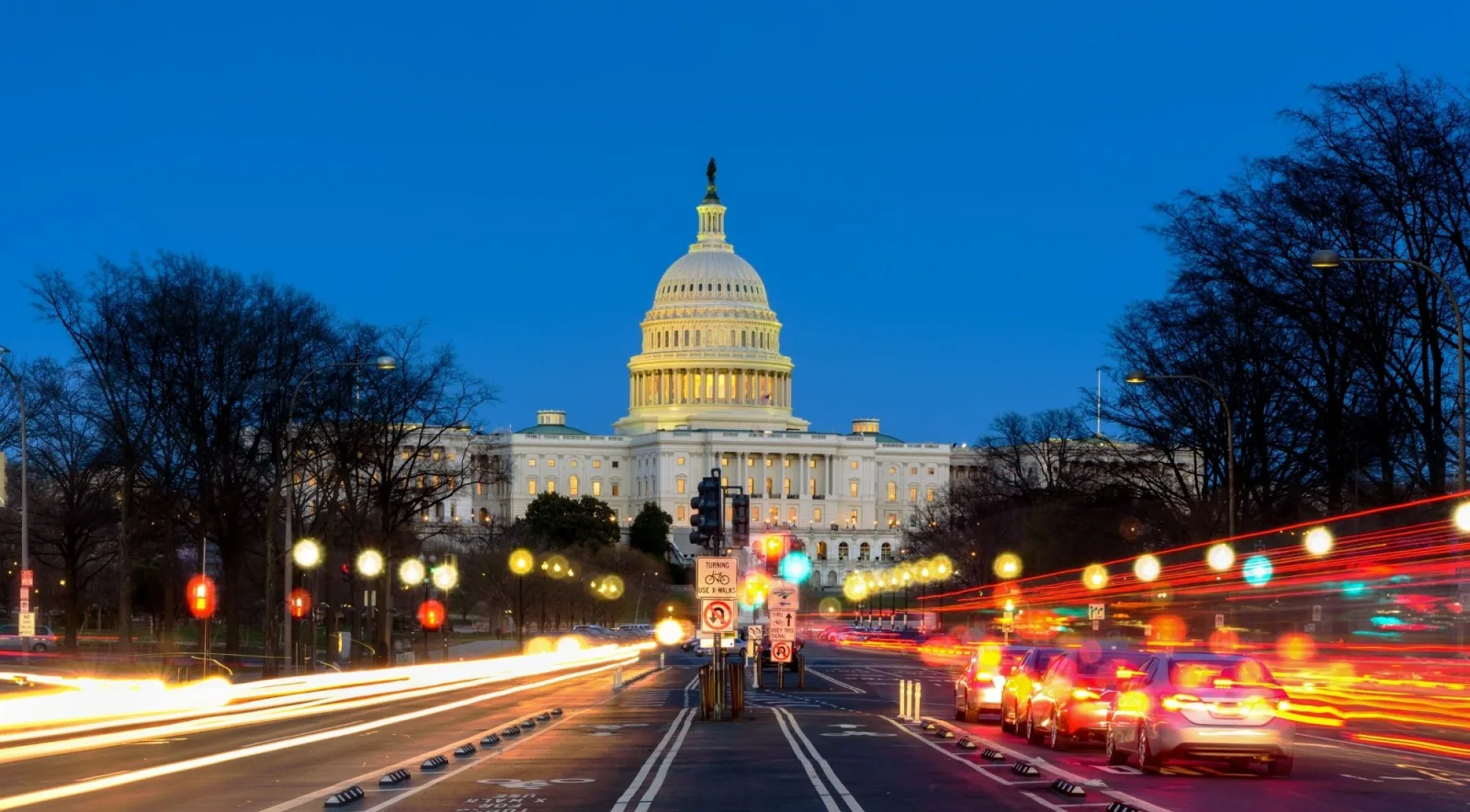 The illuminated Capitol at dusk with light trails on Pennsylvania Avenue