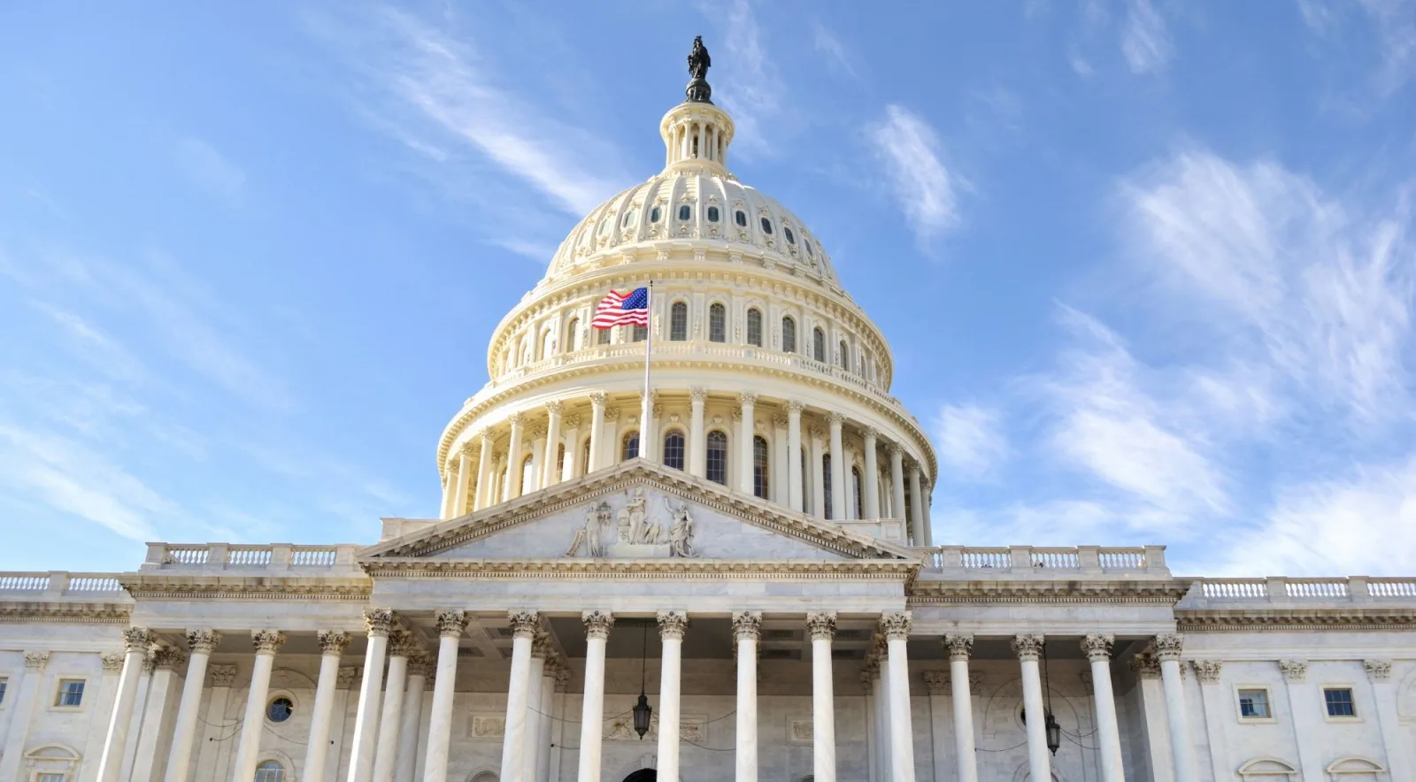 The Capitol dome and American flag against a blue sky