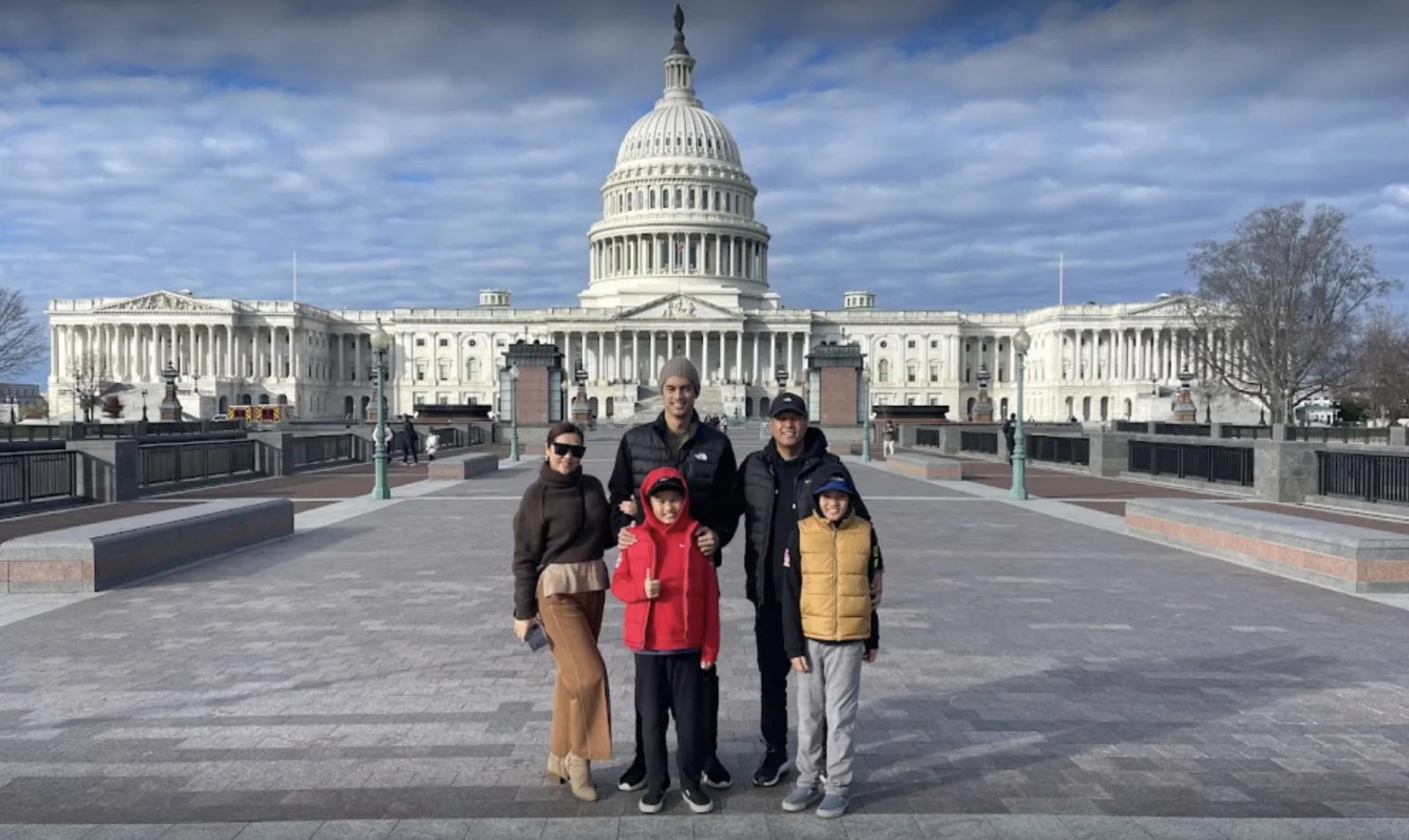 A family posing with their guide in front of the U.S. Capitol